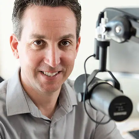 Glenn Friel sitting in front of a podcast microphone