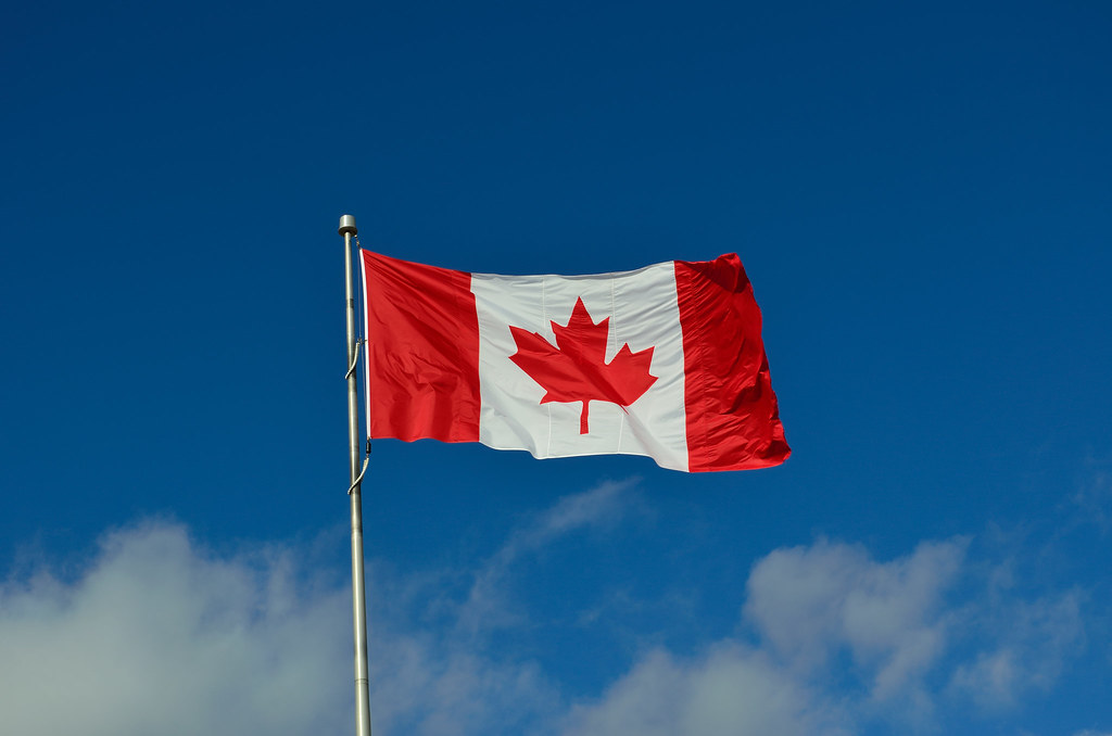 Drapeau canadien flottant sur un ciel bleu avec des nuages blancs