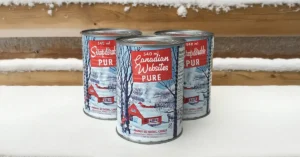 Maple Syrup cans on a snowy wood background. The can label reads Canadian Websites PURE